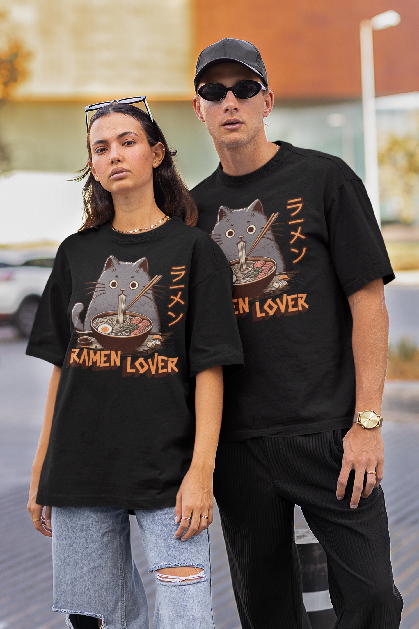 Two people wearing black t-shirts with cat graphics and 'Ramen Lover' text, standing outdoors.