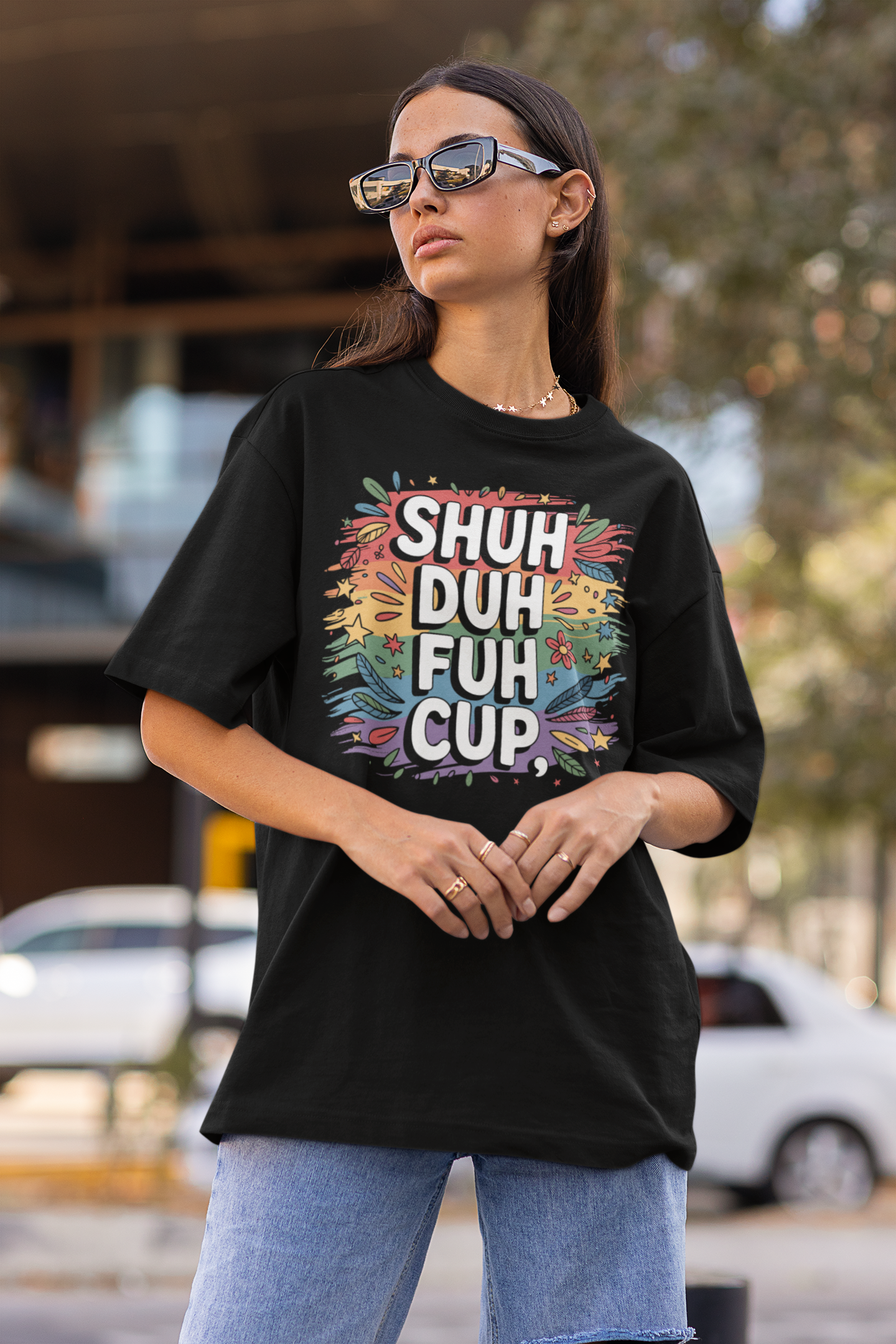 Woman wearing a black t-shirt with colorful text and graphics, standing outdoors.