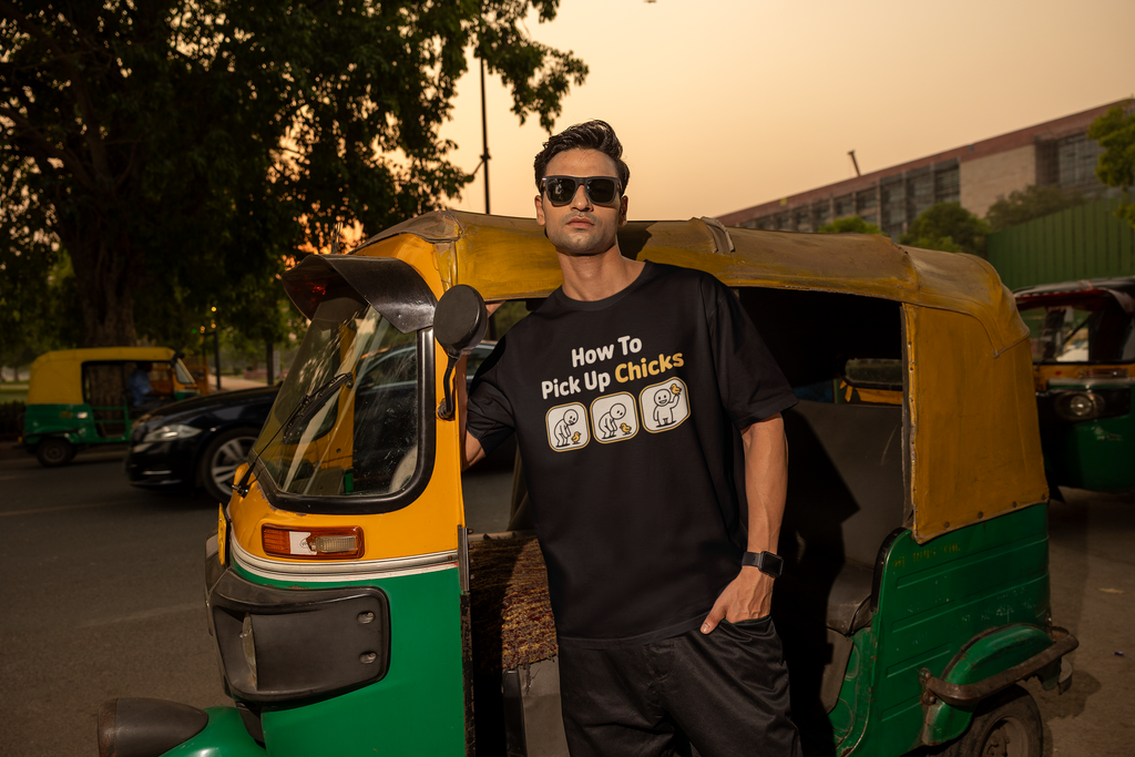 Man wearing a black t-shirt with text standing next to a green and yellow auto-rickshaw.