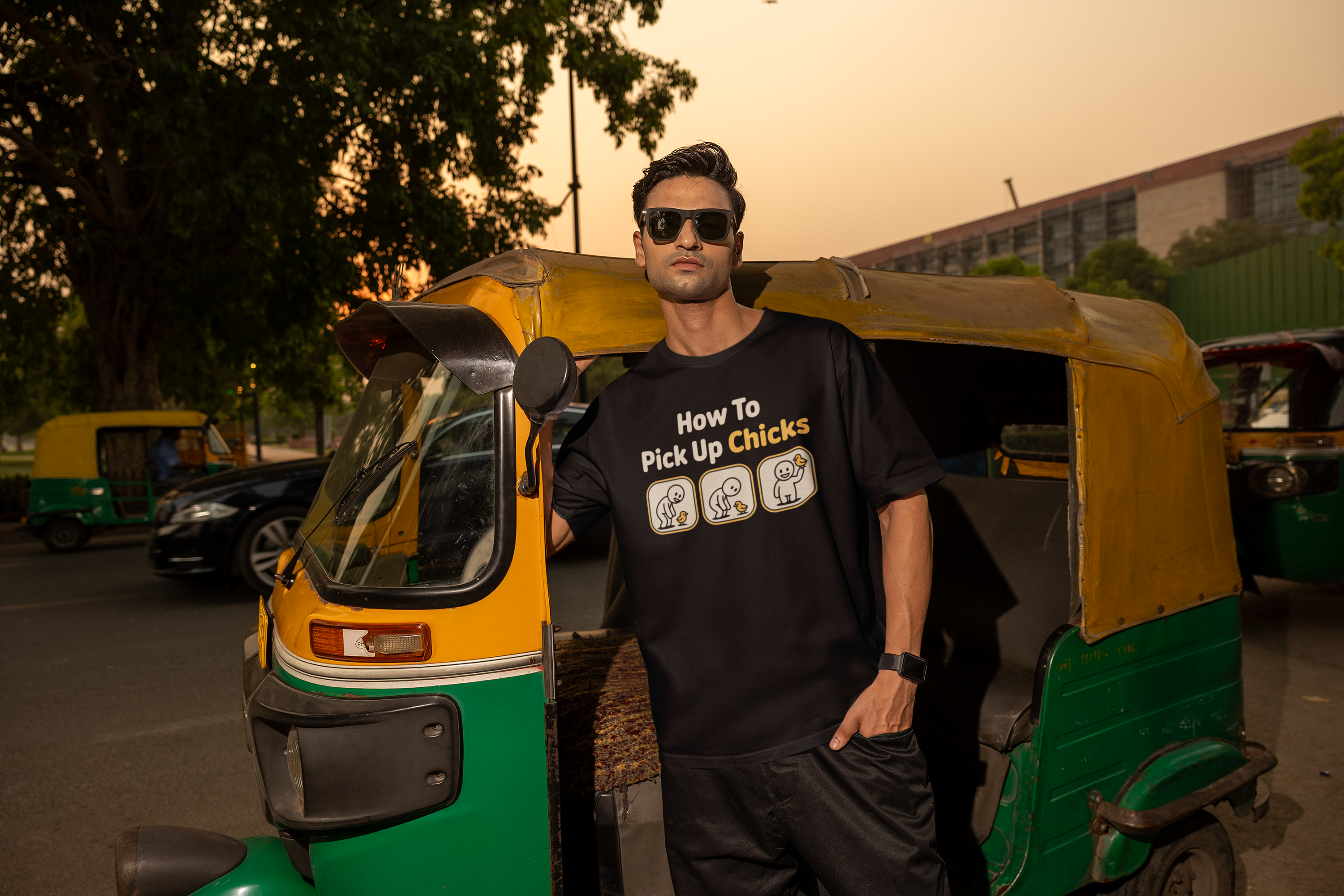Man wearing a black t-shirt with text standing next to a green and yellow auto-rickshaw.
