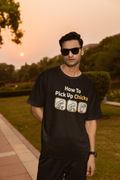 Man wearing a black t-shirt with humorous text and graphics outdoors during sunset.